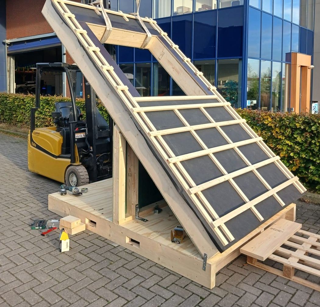Prefab dakelement met sparing voor een buitenunit, opgetild met een heftruck boven een houten vloerelement