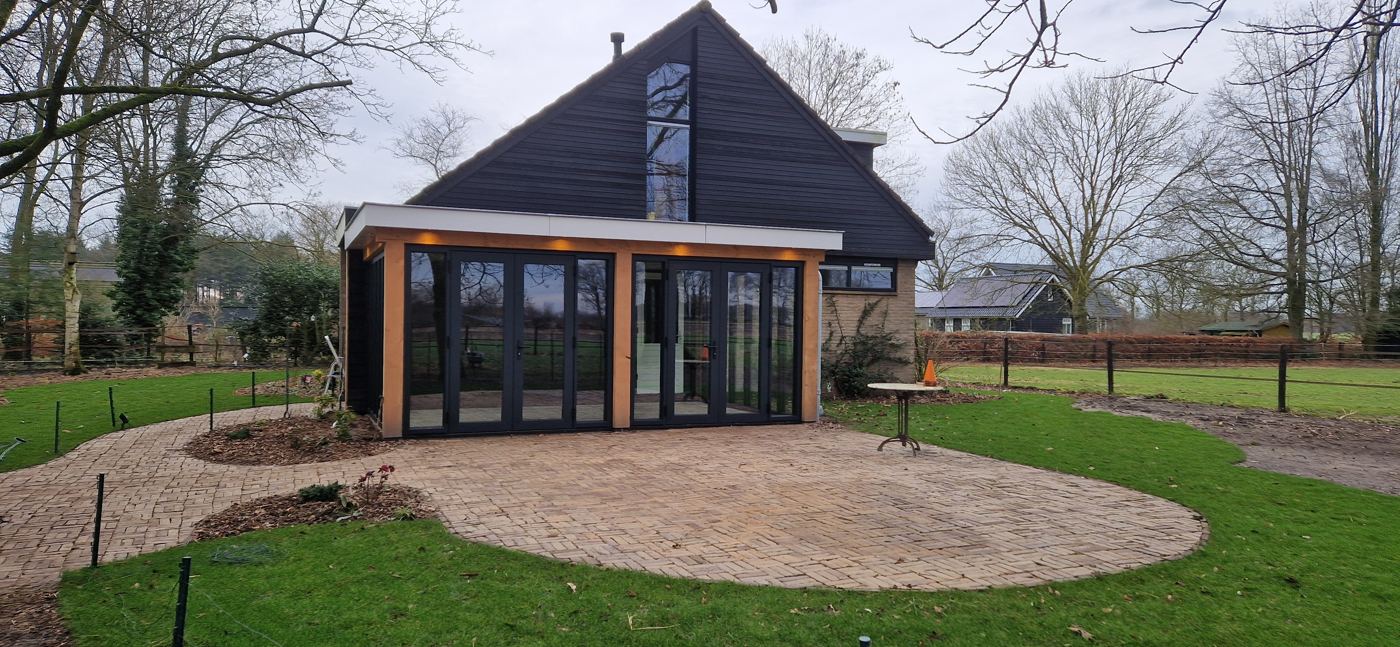 Tuinkamer met glazen schuifdeuren en houten staanders